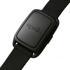 A person relaxing on a couch wearing the Apollo Neuro on their wrist, surrounded by calming decor symbolizing stress relief and better sleep
